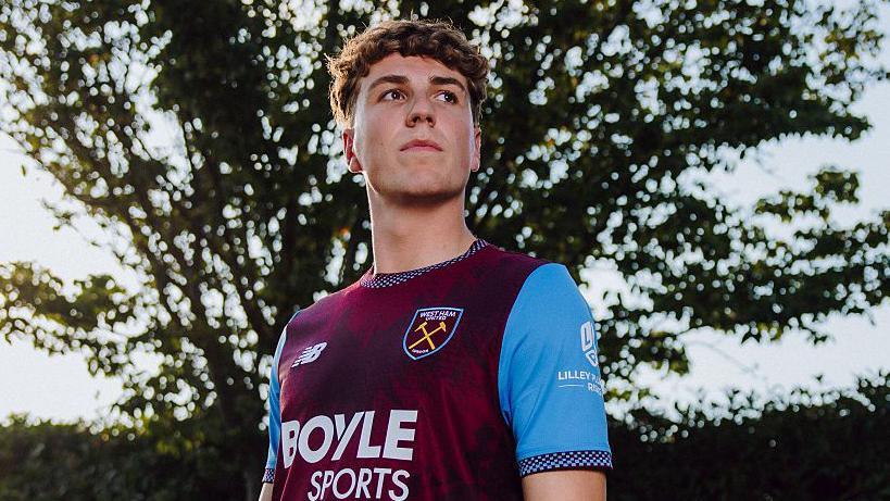 Arne Engels smiles at his unveiling by West Ham as he poses at their training ground after completing his record £22million move from Celtic.