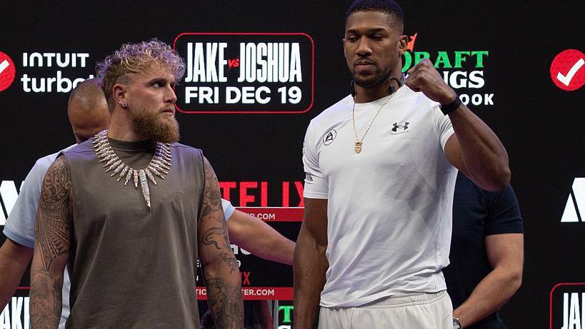Jake Paul stares at Anthony Joshua as the Briton looks straight ahead