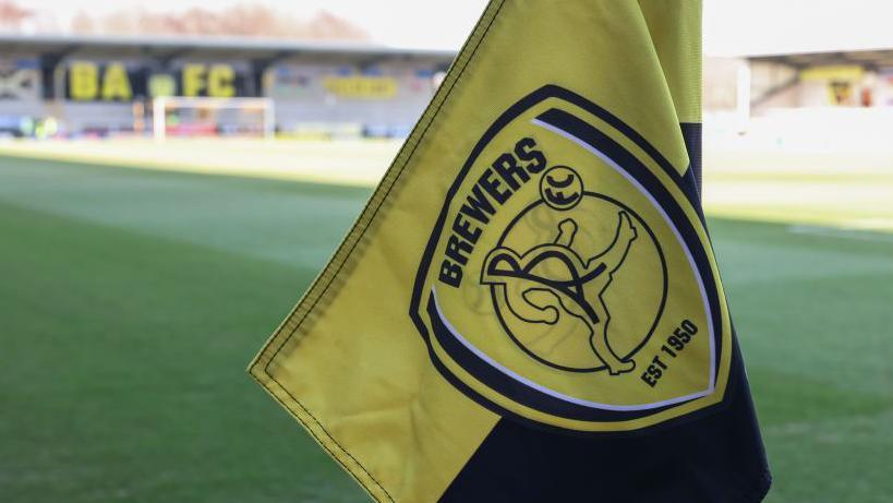 Burton Albion corner flag; one of the stands at the stadium is in the background.
