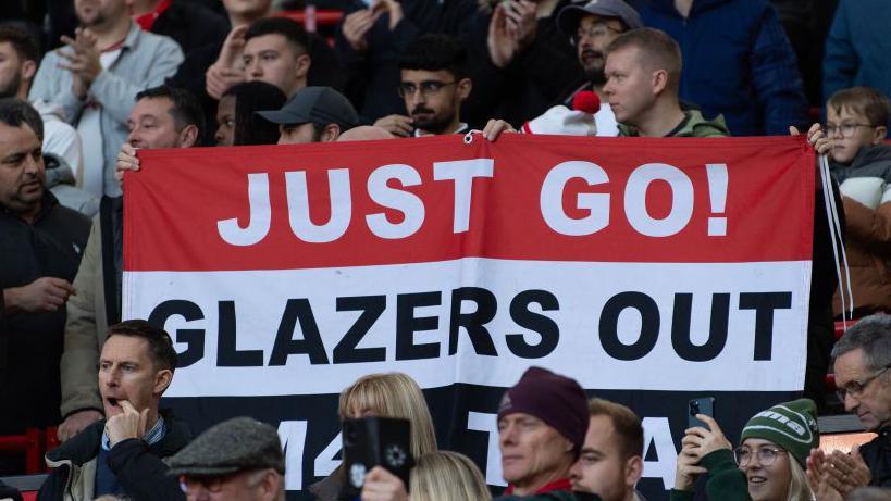 Supporters hold a banner with the words 'Just go! Glazers out'