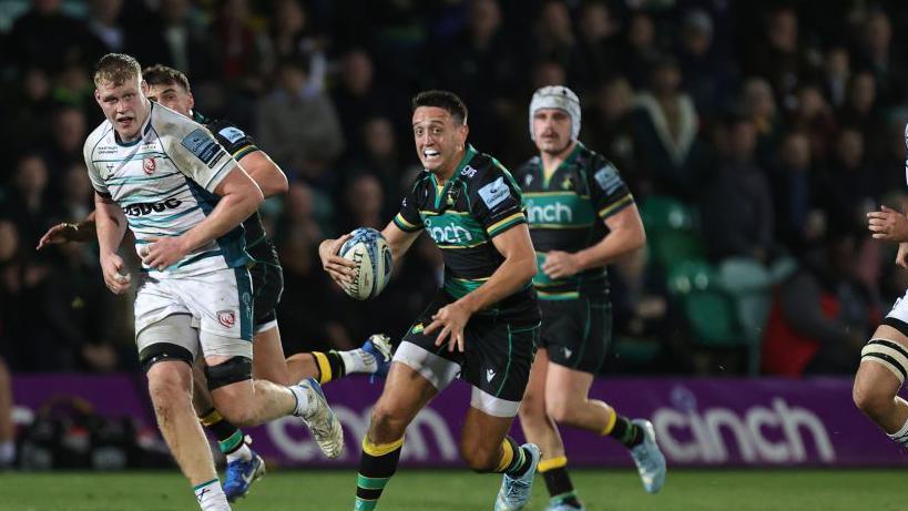 Northampton Saints scrum-half Alex Mitchell weaving with ball in hand.