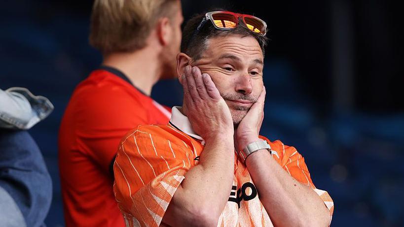 A travelling supporter shows his emotions after seeing Luton going down