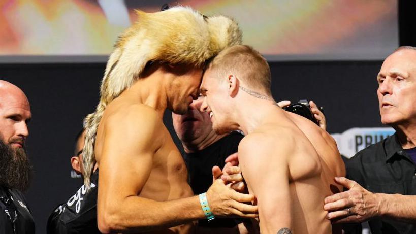 Ian Machado Garry and Shavkat Rakhmonov are separated by security at a UFC weigh-in