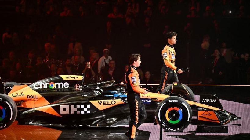 McLaren drivers Lando Norris and Oscar Piastri stood next to their team's 2025 livery