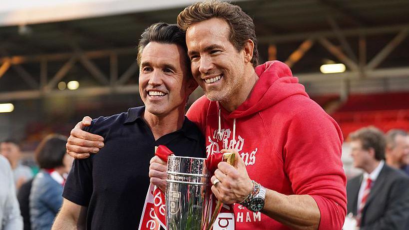 Rob Mac and Ryan Reynolds smile with trophy