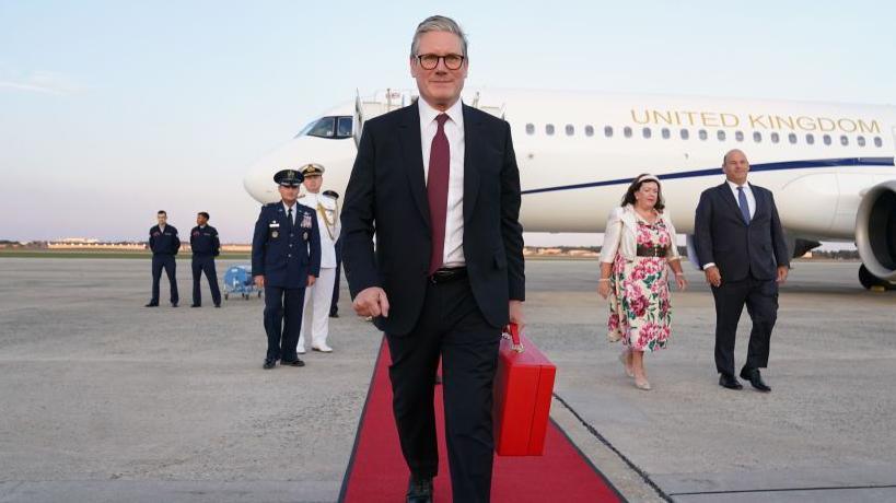 Image shows Prime Minister Sir Keir Starmer arriving at Joint Base Andrews Airport  in Washington DC, on September 12 2024 wearing a suit and tie and carrying a red briefcase 