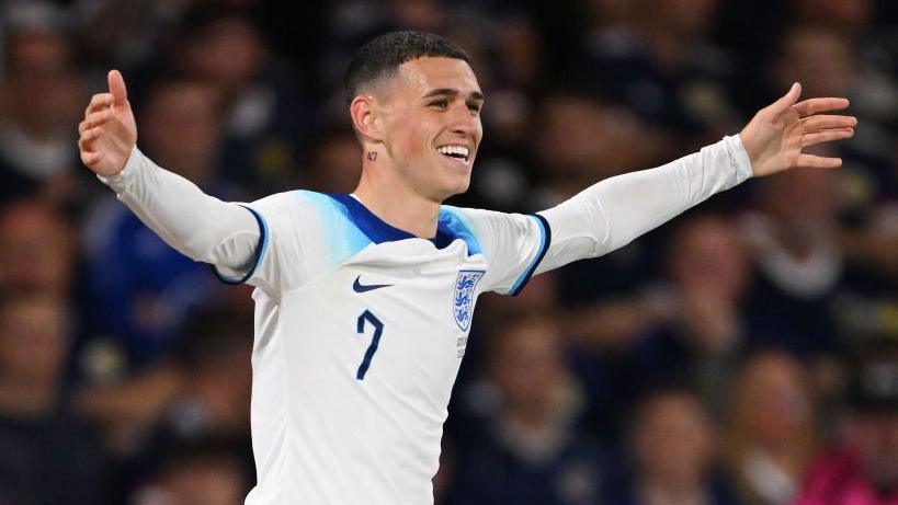 Phil Foden celebrates with his arms outstretched