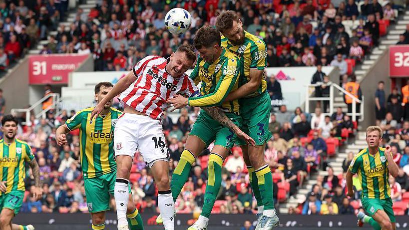 Nat Phillips and Chris Mepham leap to try and win a header against Stoke's Ben Wilmot