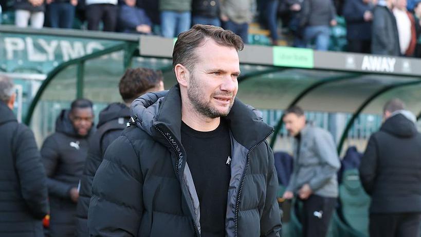 Tom Cleverley stands in the dugout area before Plymouth's match against Northampton Town.