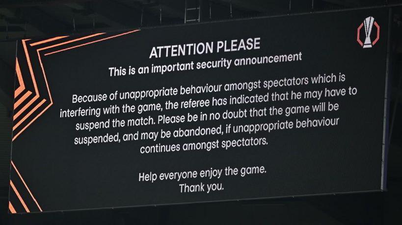 Picture of a message displayed on a screen at the stadium to explain the game was suspended because of "inappropriate behaviour amongst spectators".