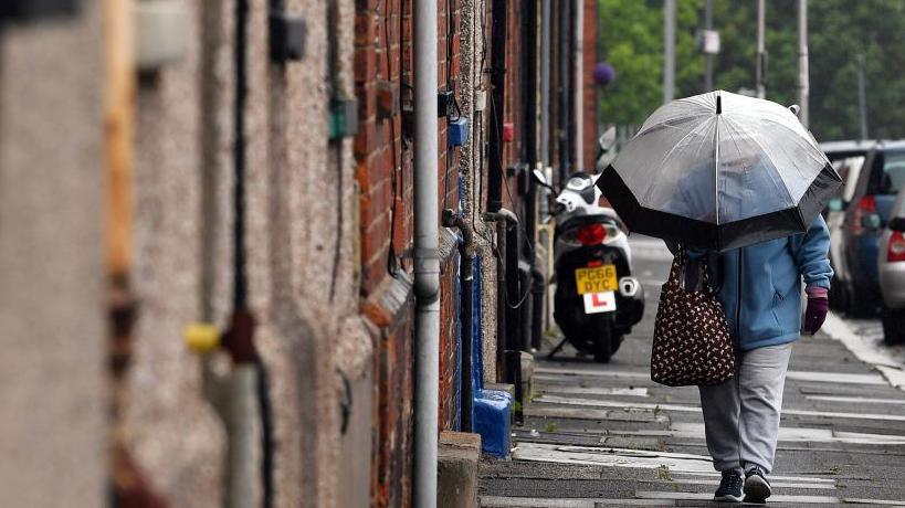 A person walks down the street holding an umbrella