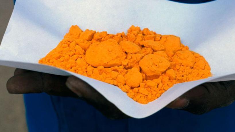 A man holds "yellowcake" at a uranium mine in Niger