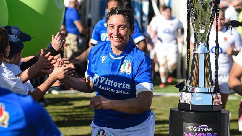 Silvia Turani high fives her team-mates as she runs past the Women's Six Nations trophy