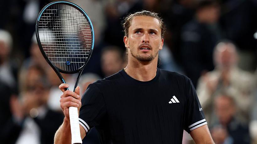 Alexander Zverev holds up a tennis racquet