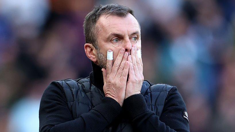 A photo of Charlton boss Nathan Jones with both his hands over his mouth