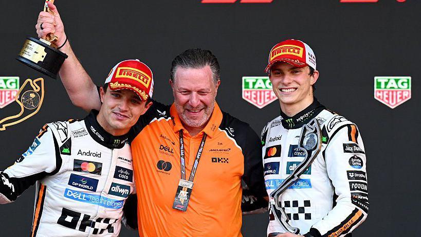 Lando Norris, Zak Brown and Oscar Piastri celebrating on the podium in Monaco