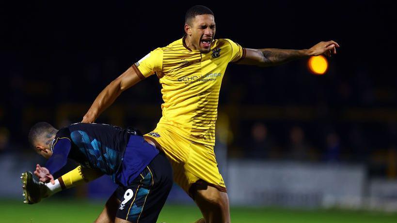 Omar Sowunmi of Sutton United tackles Courtney Baker-Richardson of Crewe Alexandra