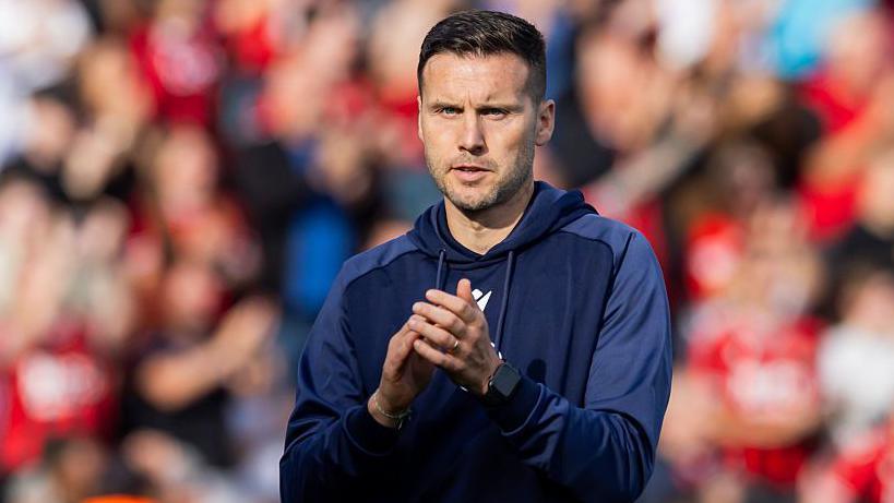 Walsall FC manager Matt Sadler wearing tracksuit applaudes players and fans after their latest win