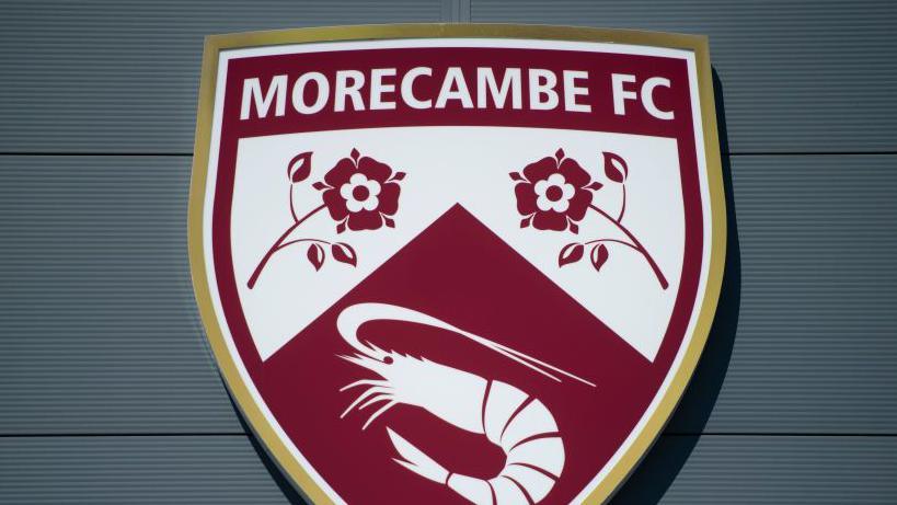 A shot of Morecambe's badge on the exterior of their Mazuma Mobile Stadium