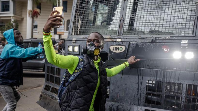 A protester takes a selfie in front of a Kenyan police water canon during a demonstration against tax hikes as Members of the Parliament vote the Finance Bill 2024 in downtown Nairoibi, on June 20, 2024. 