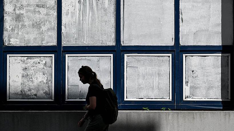 A woman walks past the windows of a school, which have been covered in white chalk