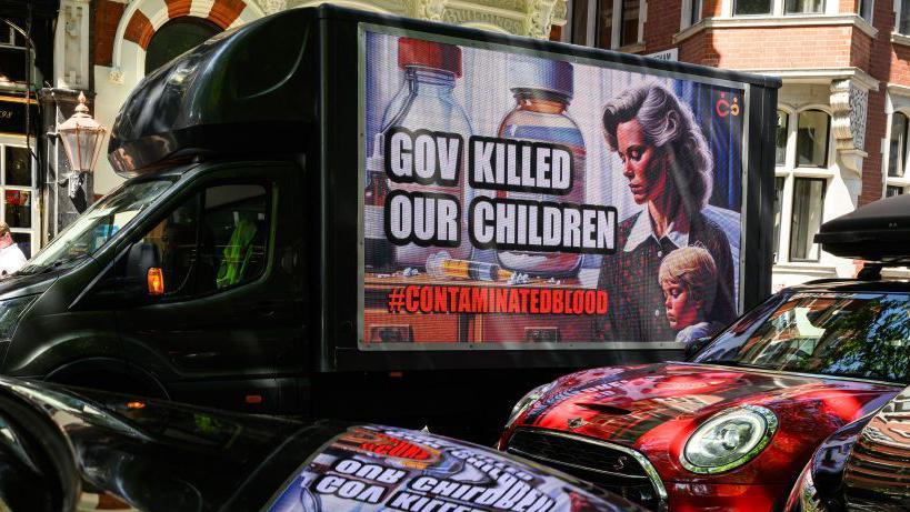 A van parked outside the infected blood inquiry in May 2020. On the side is an advertising hoarding saying "Government killed our children" and a picture of a young boy. 