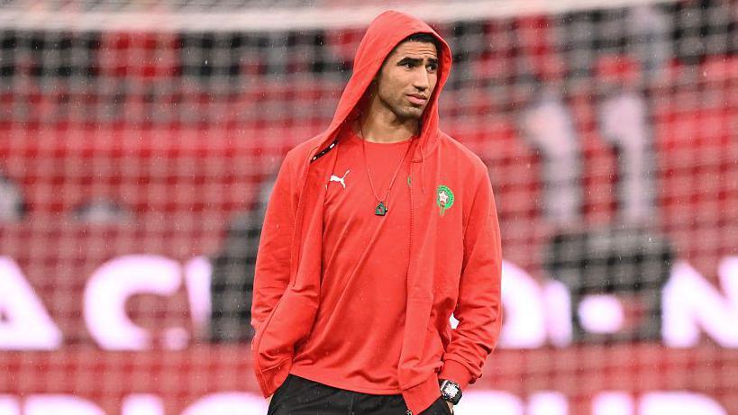 Footballer Achraf Hakimi offers a rueful look while strolling in a Morocco national football team tracksuit at the Afcon 2025.