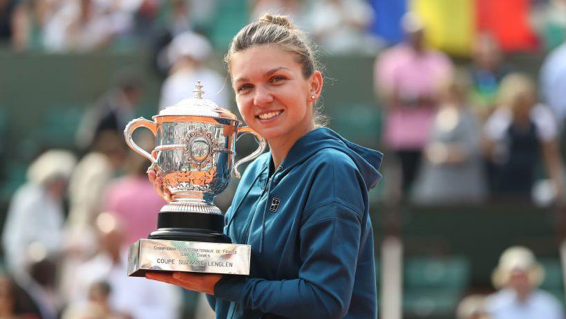 Simona Halep holds the French Open trophy - the Coupe Suzanne-Lenglen - with a Romania flag visible in the background