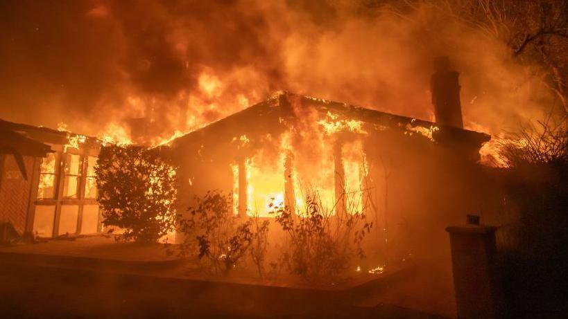 A house on fire in the Palisades neighbourhood after strong winds and dry conditions saw multipl; conflagrations ignite. 