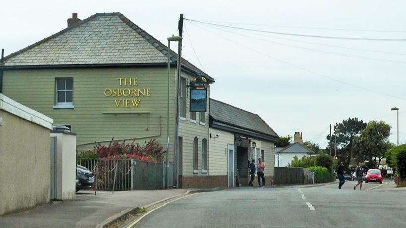 An old photo of The Osborne View pub. A pale green two-storey building with a grey pitched roof and covered in weatherboard.