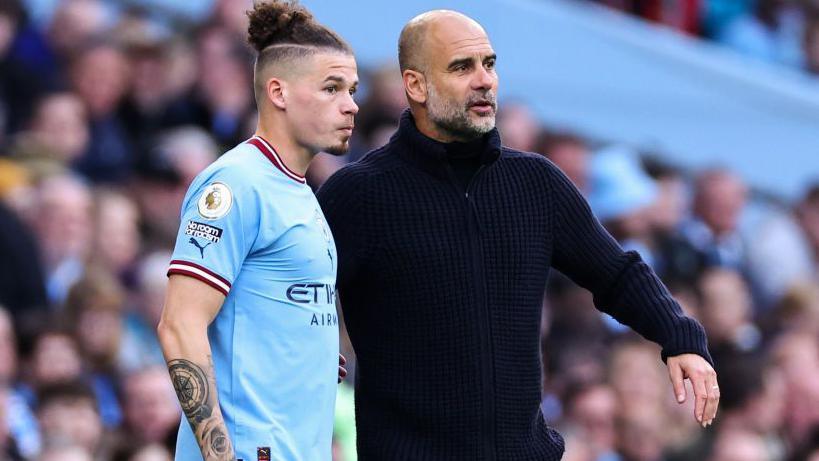 Kalvin Phillips next to Pep Guardiola on the touchline about to come on as a substitute. 