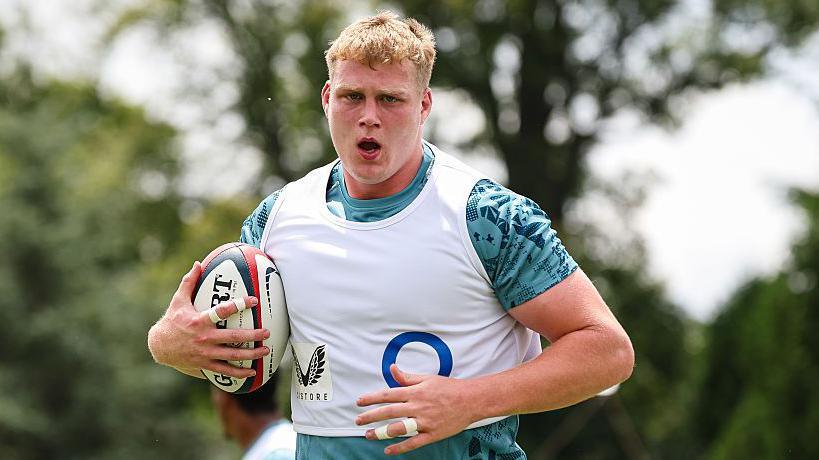 Arthur Clark runs while holding a ball during a training session with England