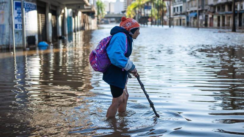 A person crosses a flooded street of the city center due to heavy rains.