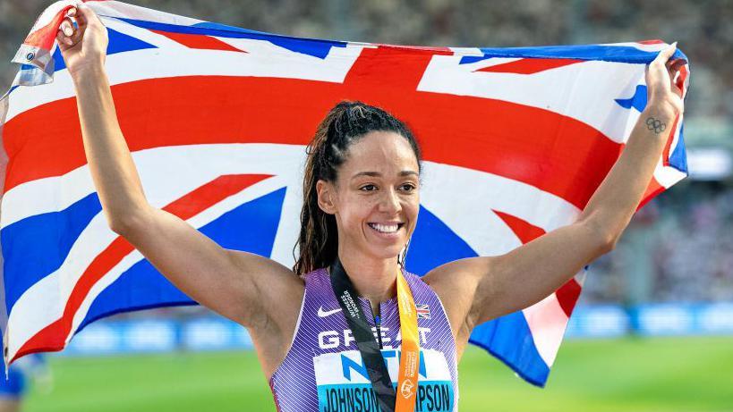 Katarina Johnson-Thompson holds aloft the Union flag in celebration