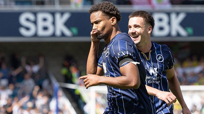 Tairyk Arconte of Millwall celebrates a goal wearing a blue shirt