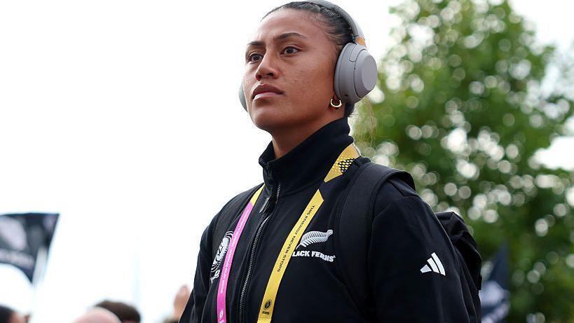 Liana Mikaele-Tu'u dressed in New Zealand-branded black training top, yellow and pink lanyard and grey headphones