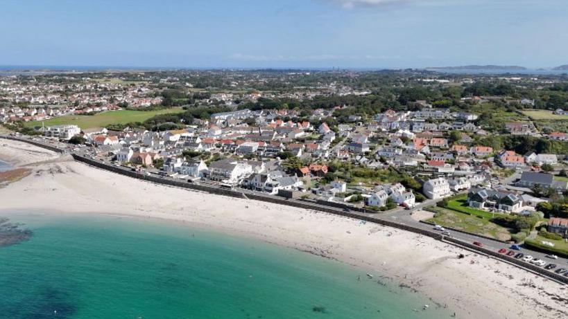An aerial shot of Guernsey from above with a blue sea and housing in the background