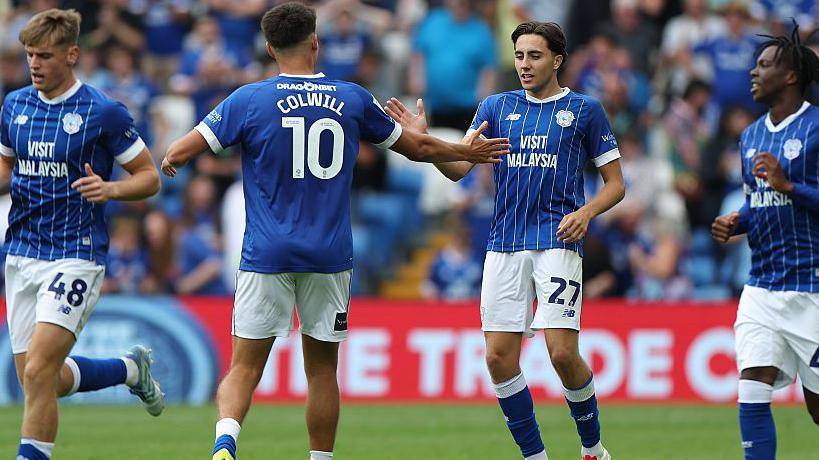 Rubin Colwill with his back to the camera celebrates with Joel Colwill in a game for Cardiff City