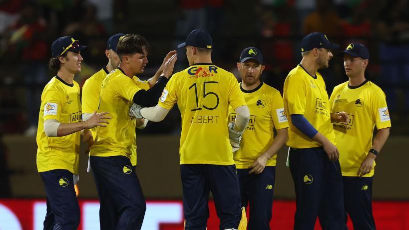 Sonny Baker of Hampshire Hawks celebrates with teammates after getting the wicket of Moeen Ali of Guyana Amazon Warriors during the ExxonMobil Guyana Global Super League T20.