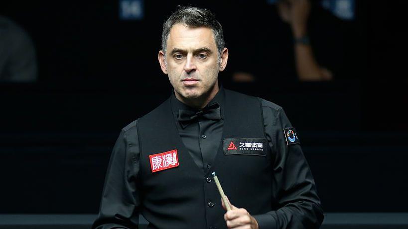 Ronnie O'Sullivan holds a snooker cue