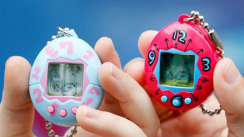 Two people holding Tamagotchis.