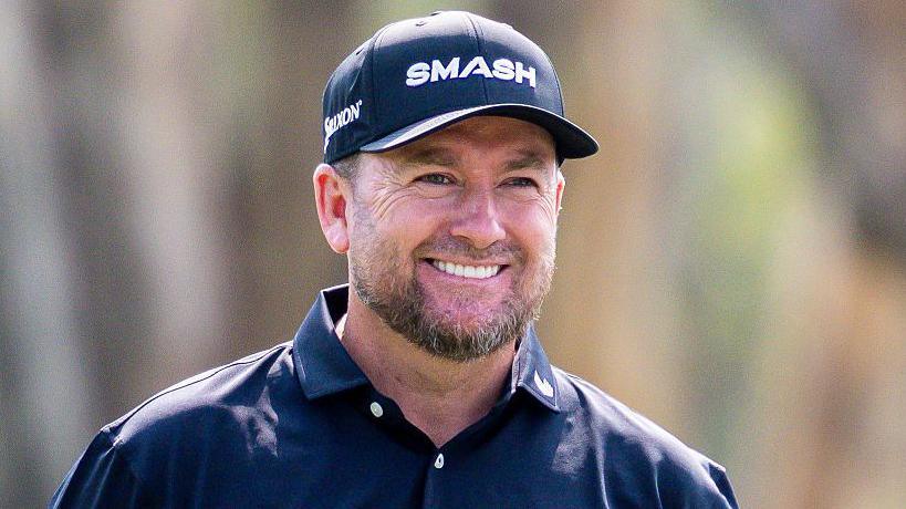 A smiling Graeme McDowell wears a dark cap and open-necked shirt
