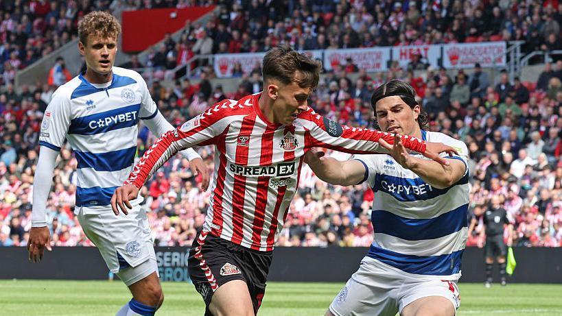 Chris Rigg dribbling past QPR players