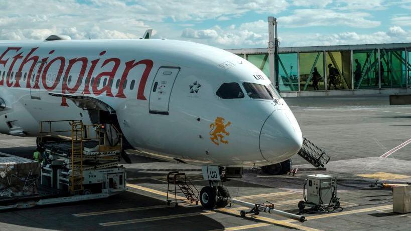 People seen walking through a tunnel with coloured glass as they go to board an Ethiopian Airlines aeroplane in Addis Ababa - 2020.