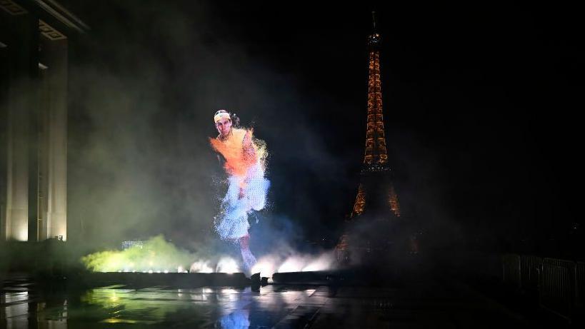 An image of Rafael Nadal is projected into the night sky in Paris, with the Eiffel Tower in the background