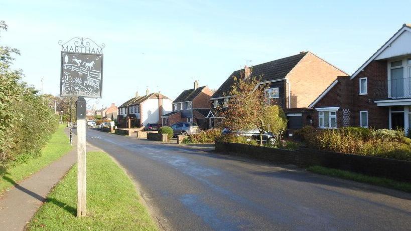 A road in Martham, Norfolk, showing a sign for Martham and a number of houses 