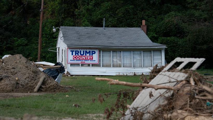 A house destroyed by a hurricane with a sign that reads 'Trump country'