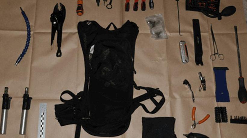 Tools, including screwdrivers, pliers, a rucksack and bolt cutters laid out on brown paper