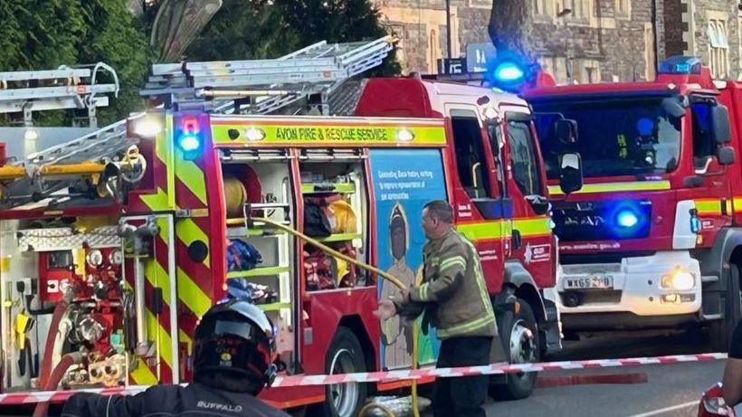 Two fire engines with a fire fighter standing next to one engine