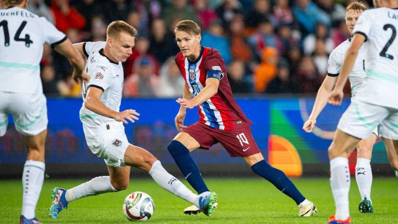 Martin Odegaard takes on Austria players in their Nations League match